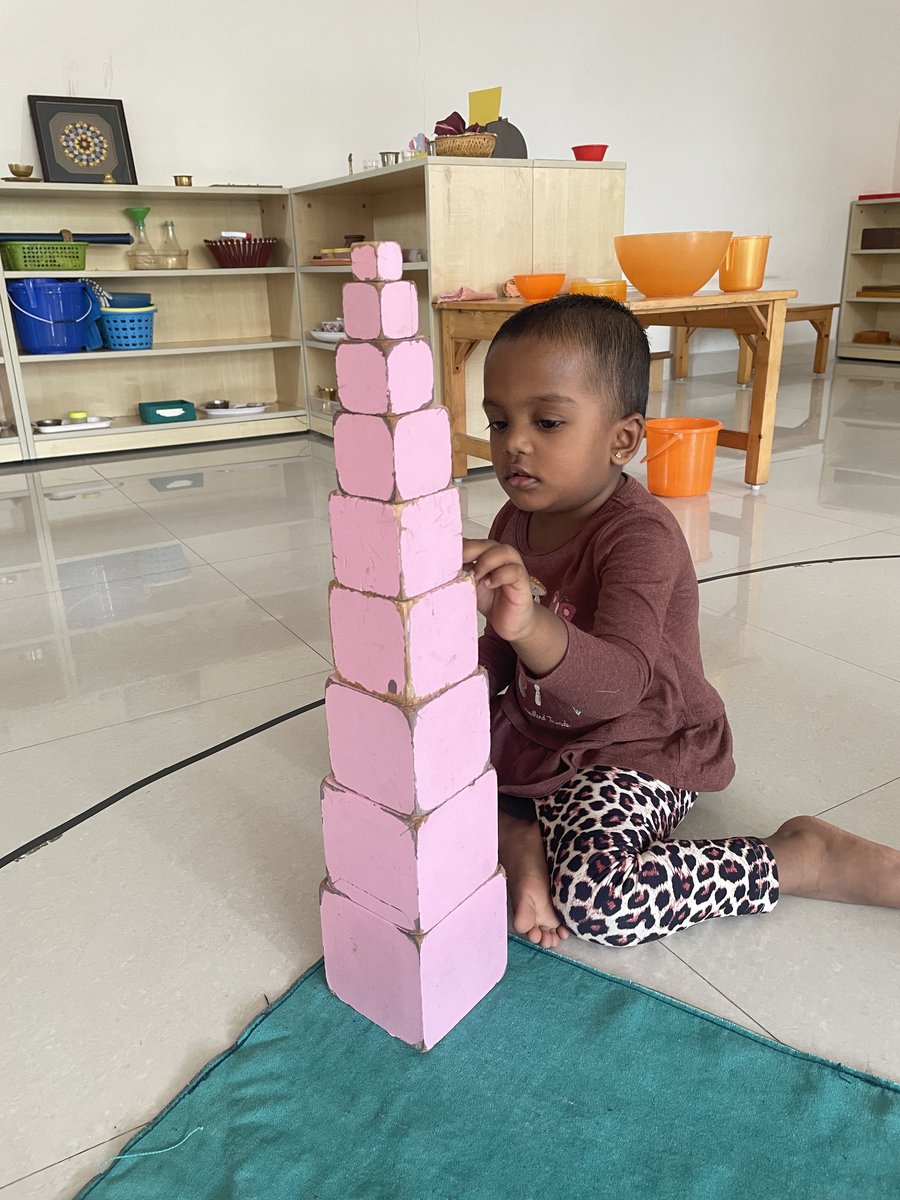 Girl building the Montessori pink tower — learning size, order, and concentration